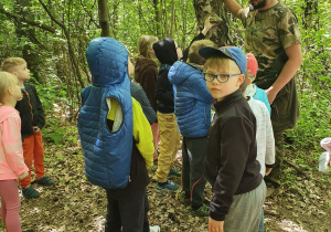 Przewodnik stoi wśród dzieci w lesie
