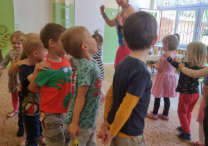 Dzieci stojące w kole, naśladują kroki zumby prezentowane przez instruktorkę