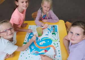 Dzieci wykonują pracę plastyczną z wykorzystaniem farb i plastikowych butelek