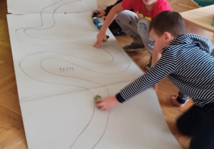 Dzieci tworzą trasę dla samochodów z papieru