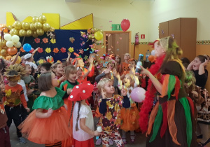 Dzieci przebrane w stroje jesienne oraz Pani jesień tańczą na balu