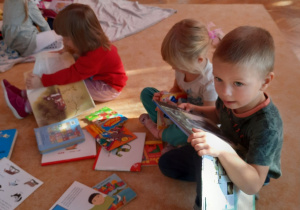 dzieci oglądają książki na dywanie