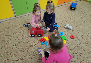Dzieci bawią sie klockami i samochodem na dywanie
