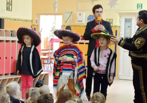 Dzieci przebrane w stroje meksykańskie oraz prowadzący audycję muzyczną stoją przed widownią