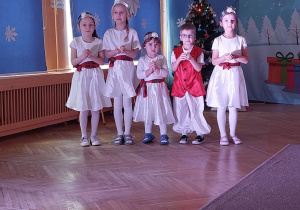Dzieci ubrane w białe, świąteczne stroje pozują do zdjęcia