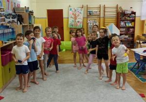 Dzieci stojące w dwóch rzędach, przygotowują się do biegu z woreczkami gimnastycznymi