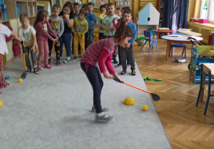 Dzieci uczestniczą w zawodach sportowych: uderzenie piłeczki kijem do hokeja