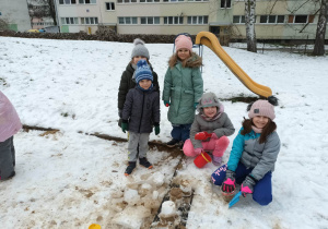 Dzieci bawią się śniegiem w ogrodzie przedszkolnym