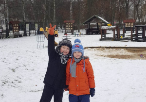 Chłopcy pozują do zdjęcia na śniegu w ogrodzie przedszkolnym