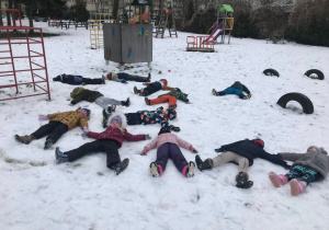 Dzieci robią "aniołka na śniegu"