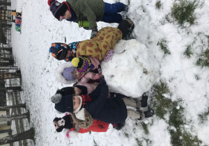 dzieci toczą dużą kule ze śniegu