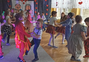 Dzieci z grupy V ubrane w kolorowe stroje tańczą twista na środku sali