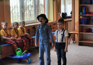 Dziecko przebrane za dziadka stoi na "scenie przedszkolnej" obok kolegi.