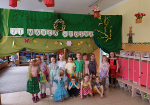 Dzieci pozują do zdjęcia na tle dekoracji wiosennej z marzanną