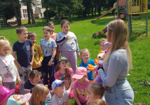 Prowadząca z pomocą maskotki prowadzi warsztaty w ogrodzie przedszkolnym o higienie jamy ustnej