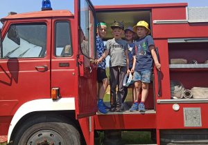 Dzieci pozują do zdjęcia w wozie strażackim