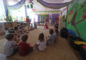 Prowadząca warsztaty oraz dzieci siedzą na dywanie "w kole"