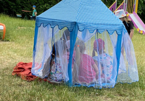 Dzieci siedzące w niebieskim namiocie