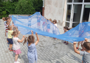 Dzieci podrzucające niebieską chustę