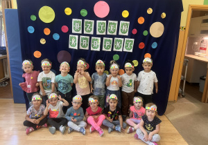 Dzieci pozują do zdjęcia w Dniu Kropki na tle dekoracji przedstawiającej różnokolorowe kropki