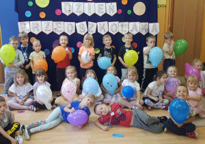 Dzieci pozują do zdjęcia z balonami na tle dekoracji