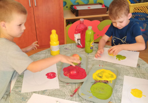Dzieci stemplują za pomocą jabłka na kartce papieru