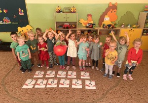 Dzieci pozują do zdjęcia stojąc za napisem Dzień Jabłka