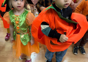 Dzieci przebrane w jesienne stroje tańczą na balu jesieni.