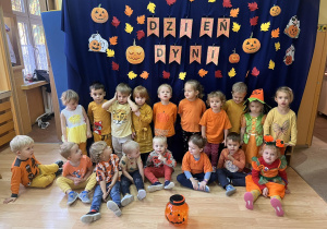 Dzieci przebrane w stroje w kolorze pomarańczowympozują do grupowego zdjęcia