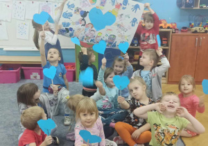 Dzieci pozują do wspólnego zdjęcia trzymając w rękach niebieskie serca oraz plakat