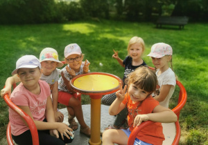 Dzieci kręcą się na huśtawce w ogrodzie przedszkolnym