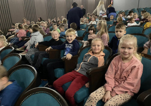 Dzieci siedzą na fotelach w teatrze