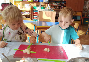 Dzieci kroją owoce na deseczkach do sałatki