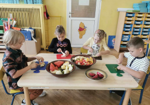 Dzieci kroją owoce na deseczkach do sałatki