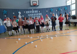 Dzieci wykonują utwór i rzucają śnieżkami z bibuły