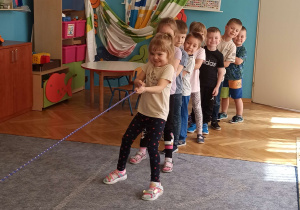 Dzieci przeciągają linę w sali przedszkolnej