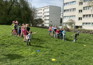 Dzieci biorą udział w konkurencji sportowej: bieg slalomem w ogrodzie przedszkolnym