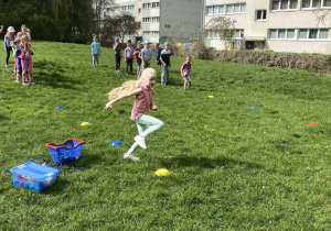 Dzieci biorą udział w konkurencji sportowej: bieg slalomem w ogrodzie przedszkolnym