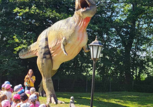 Dzieci zmierzają w kierunku sylwety dinozaura