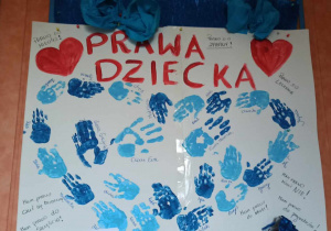 Praca plastyczna przedstawiająca odciśnięte dłonie dzieci oraz napis