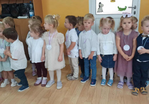Maluszki ubrane w odświętne stroje stoją w holu przedszkola