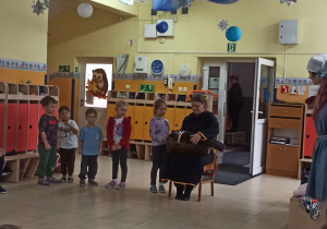 Artystka grająca na lirze zaprasza dzieci do wspólnego grania na instrumencie