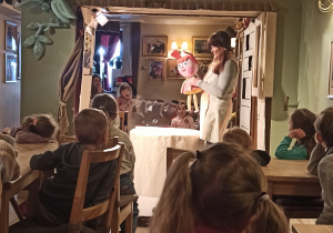 Dzieci oglądają przedstawienie. Aktorka prezentuje lalkę teatralną