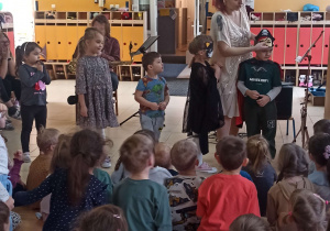 Artystka zakłada maski karnawałowe dzieciom stojącym na scenie