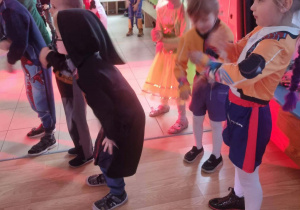 Dzieci przebrane w karnawałowe stroje tańczą na balu