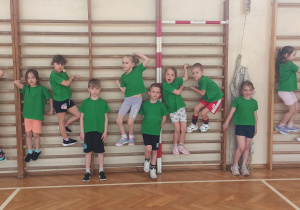 Dzieci pozują do zdjęcia na drabinkach w sali gimnastycznej