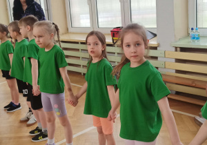 Dzieci trzymają się za ręce i przechodzą przez obręcz