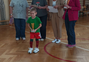 Kapitan drużyny odbiera puchar z rąk dyrektora Szkoły Podstawowej nr 84