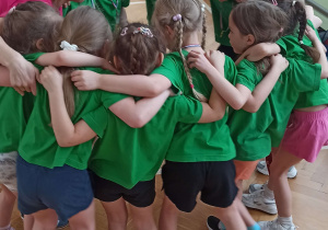 Dzieci ustawione w kole, trzymają się za ramiona