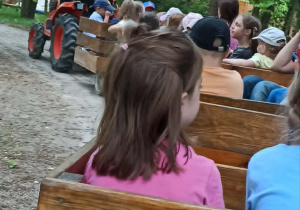 Przejażdżka dzieci drewnianymi wagonikami ciągniętymi przez traktor